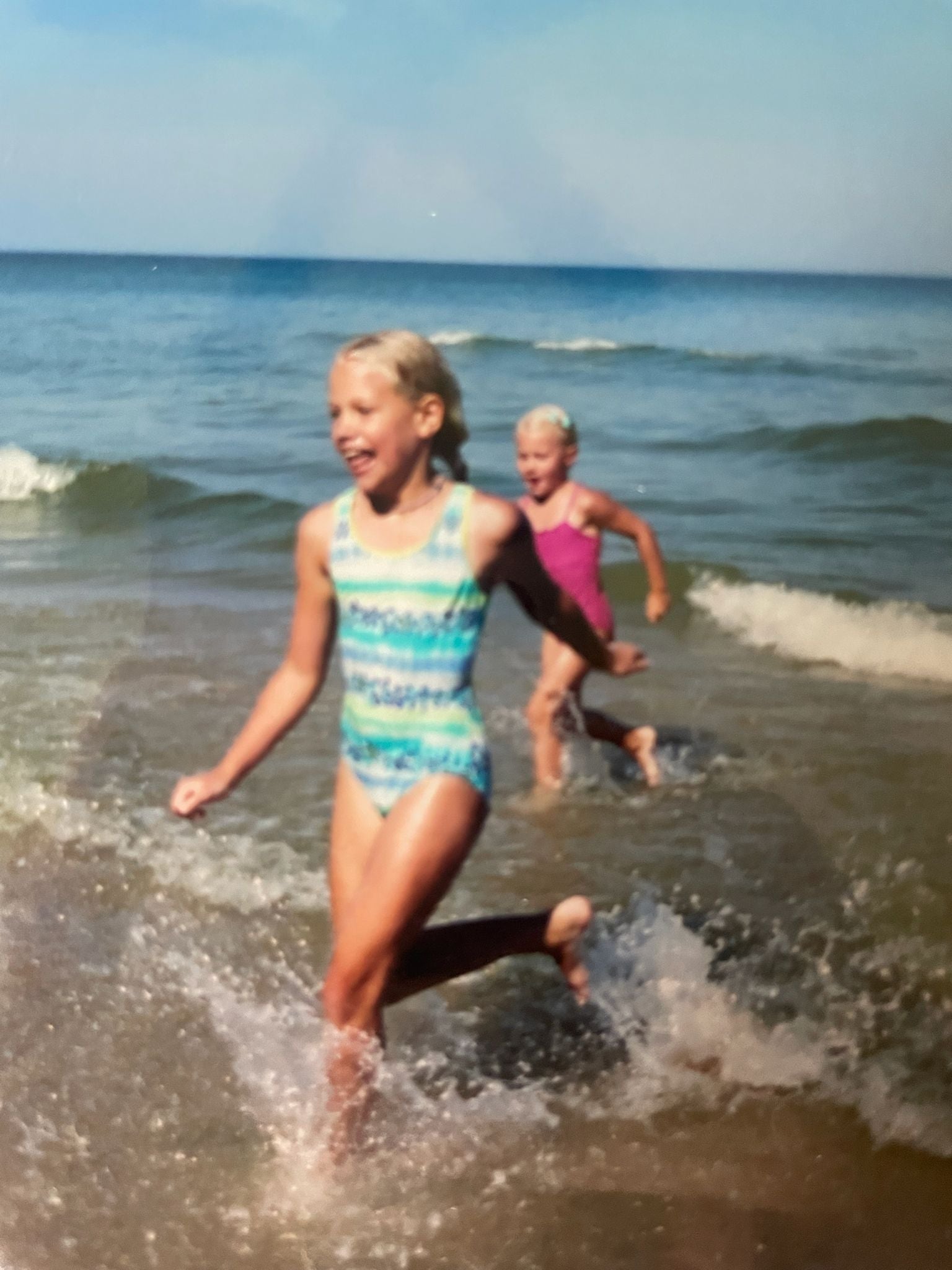 Two children playing in the ocean on a sunny day.